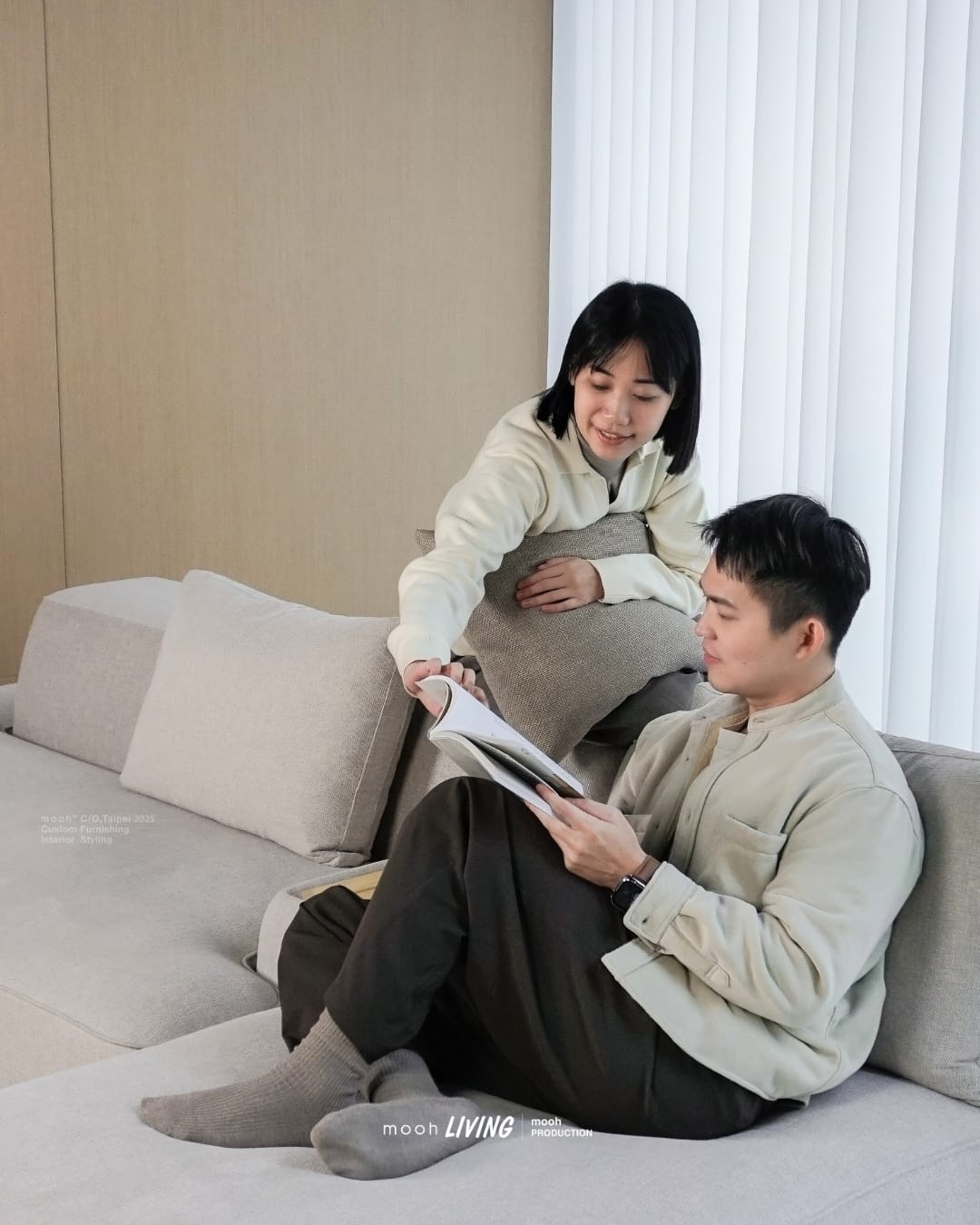 mooh Living 佛林斯｜三人沙發生活情境,特寫一對男女,女生坐在沙發寬厚的椅背上和正在看書的男生互動